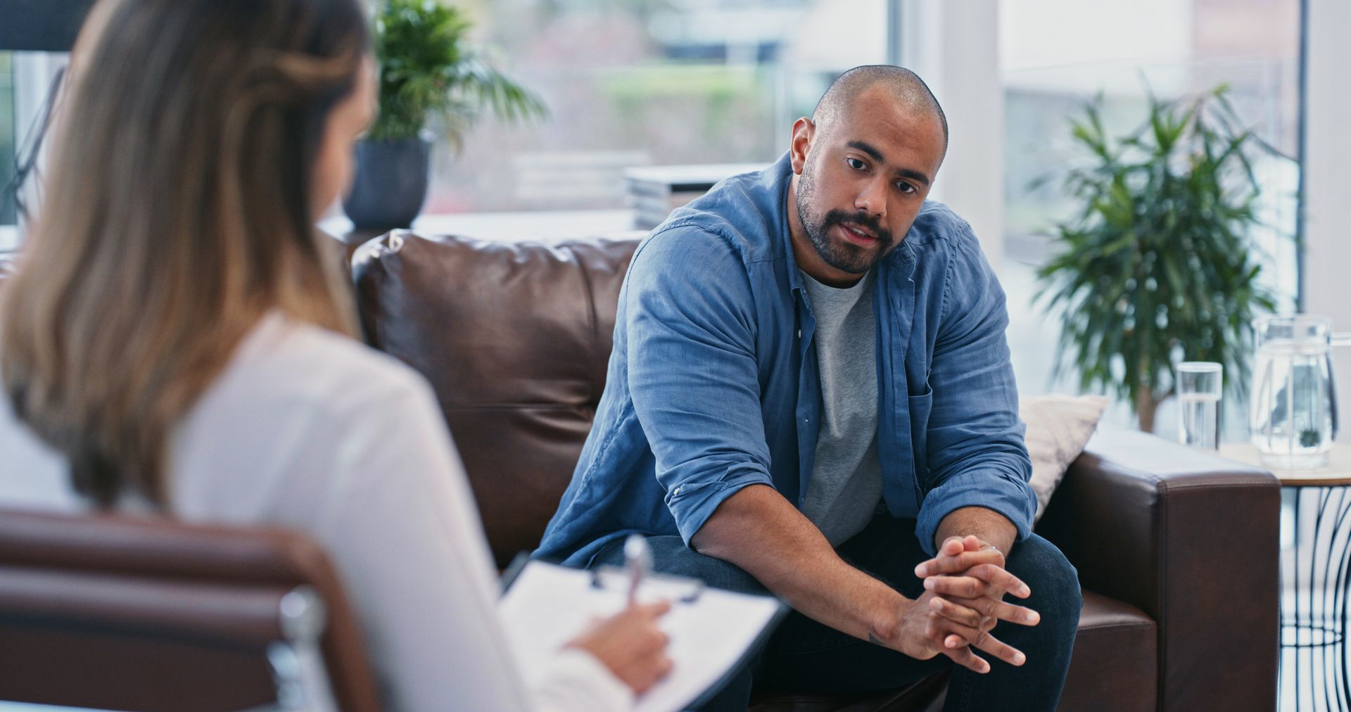A man is sitting on a couch talking to a woman.