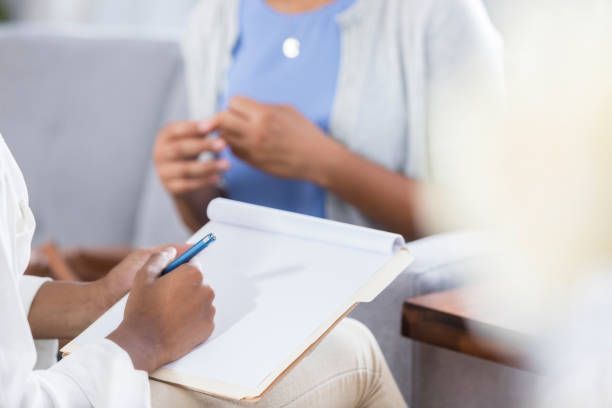 A doctor is taking notes while talking to a patient.