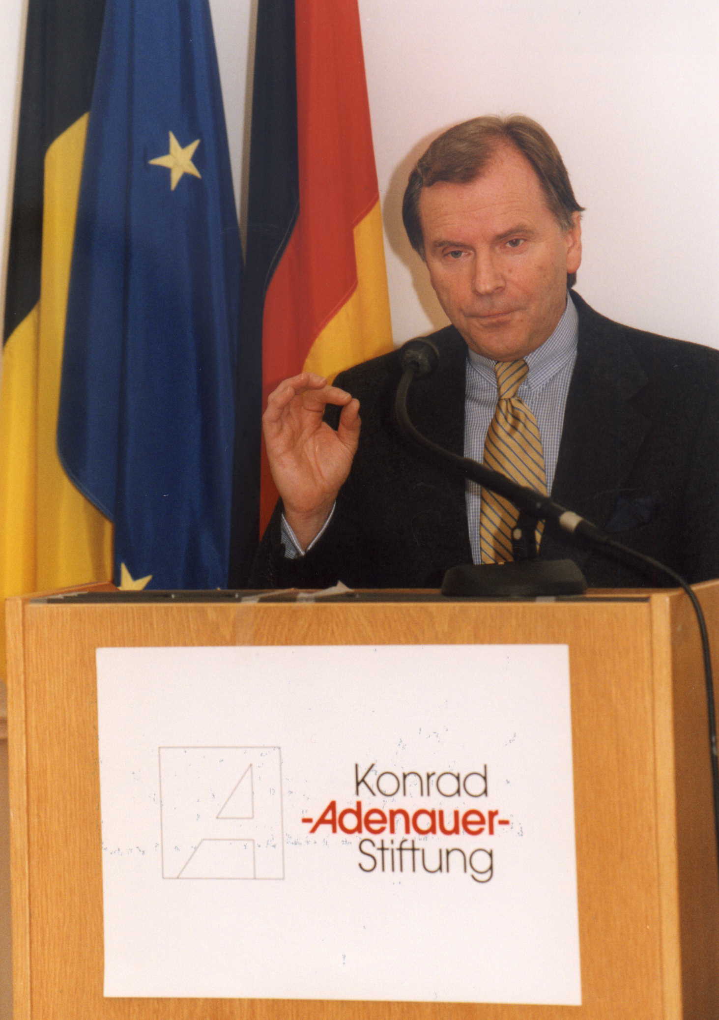 A man stands behind a podium that says konrad adenauer stiftung