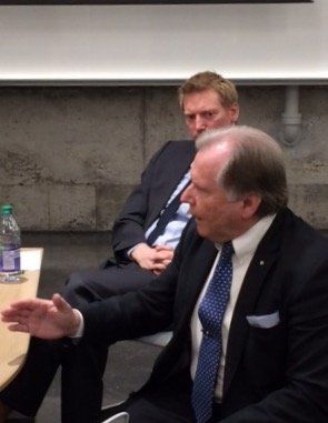 Ein Mann in Anzug und Krawatte spricht mit einem anderen Mann