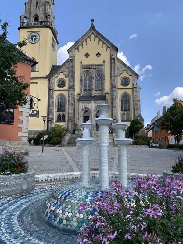 Eine Kirche mit einem Glockenturm und einem Brunnen davor