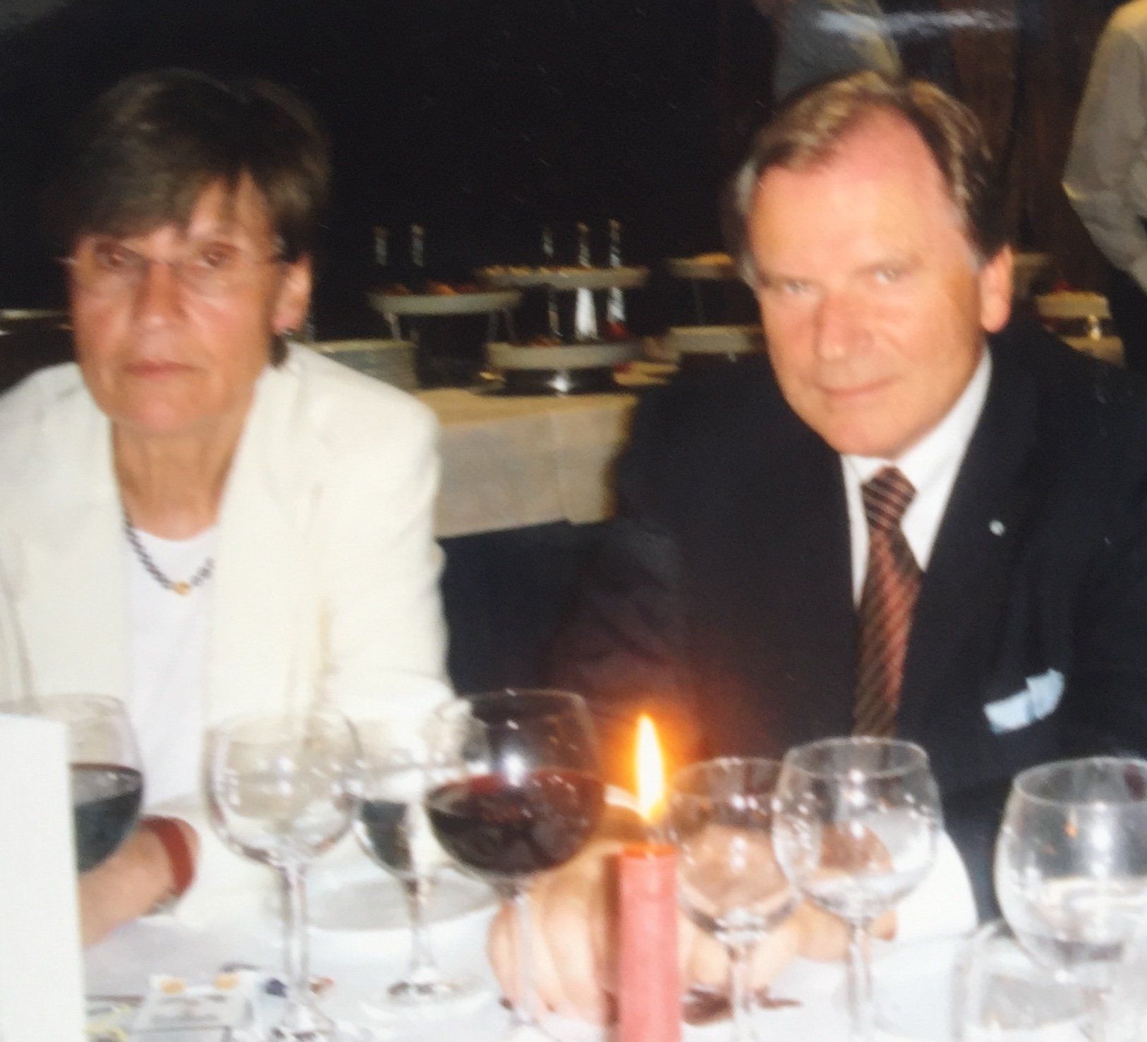 Ein Mann und eine Frau sitzen an einem Tisch mit Weingläsern und einer Kerze