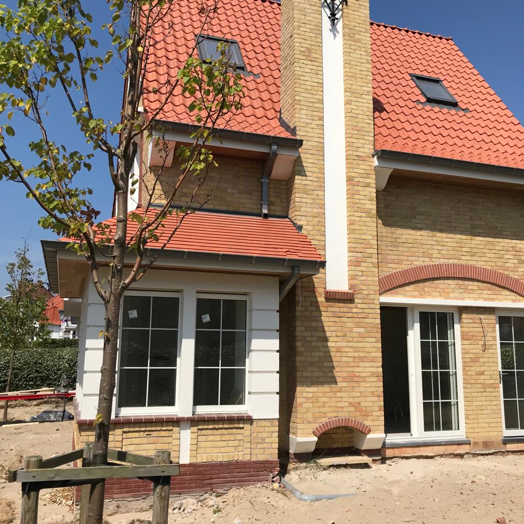 Ein Backsteinhaus mit rotem Dach und einem Baum davor