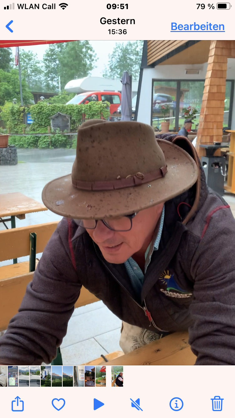 Ein Mann mit Hut und Brille sitzt an einem Tisch.