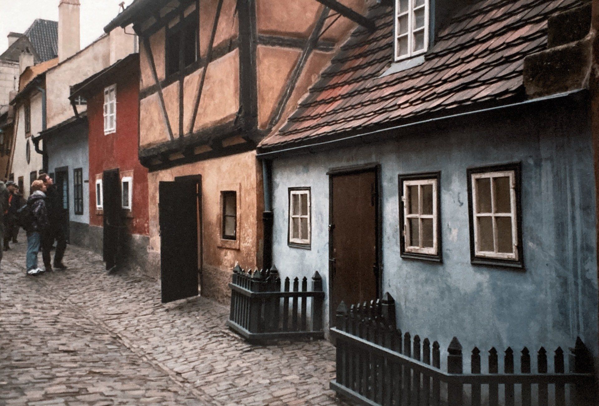 Eine Gruppe von Menschen geht eine Kopfsteinpflasterstraße vor einer Häuserreihe entlang.