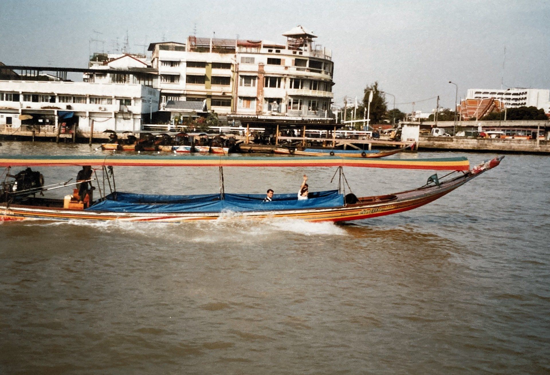 Ein Boot schwimmt auf einem Gewässer mit Gebäuden im Hintergrund