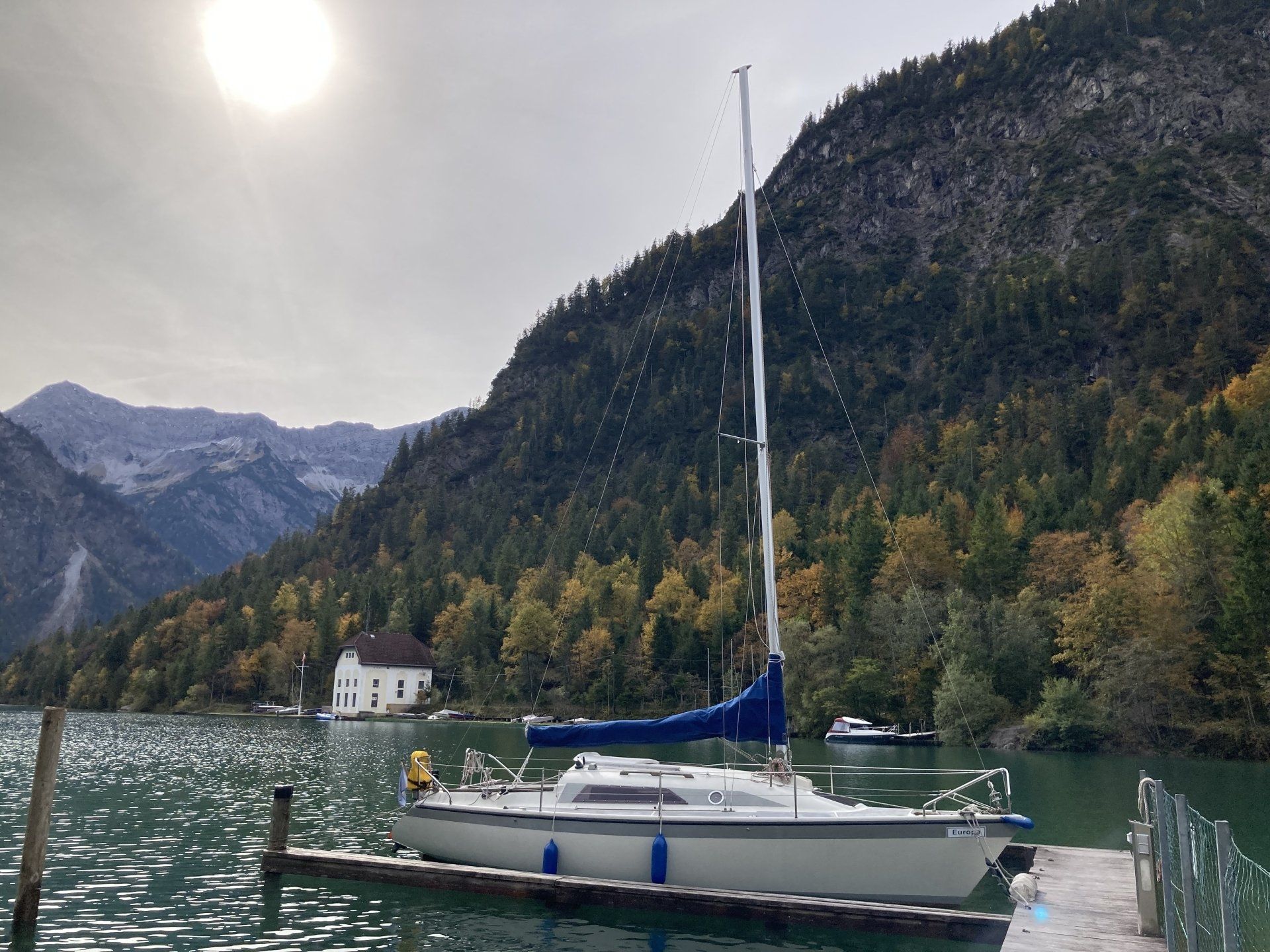 Ein Segelboot liegt an einem Dock mit Bergen im Hintergrund