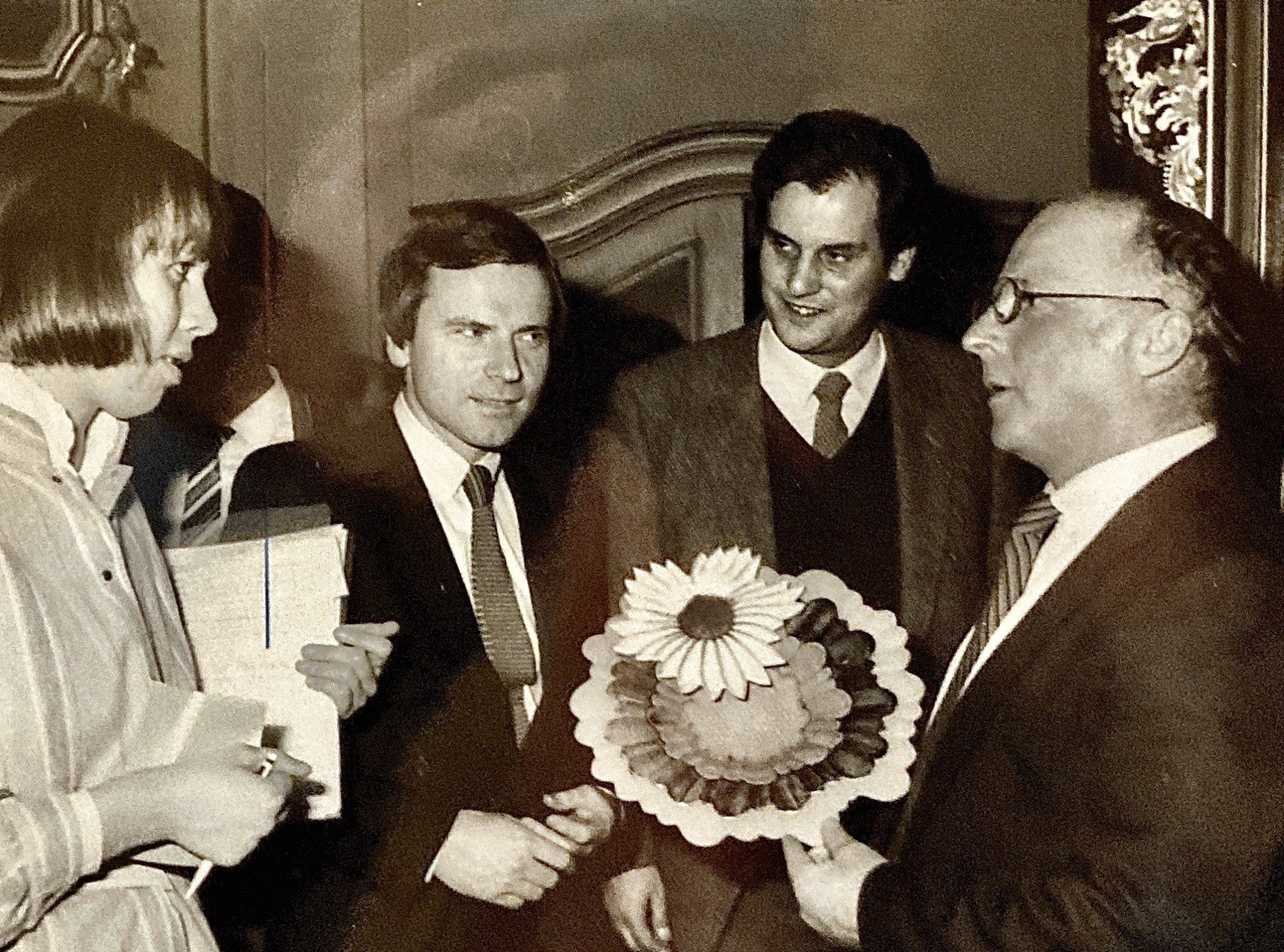 Eine Gruppe von Männern steht um einen Mann herum, der einen Blumenstrauß hält