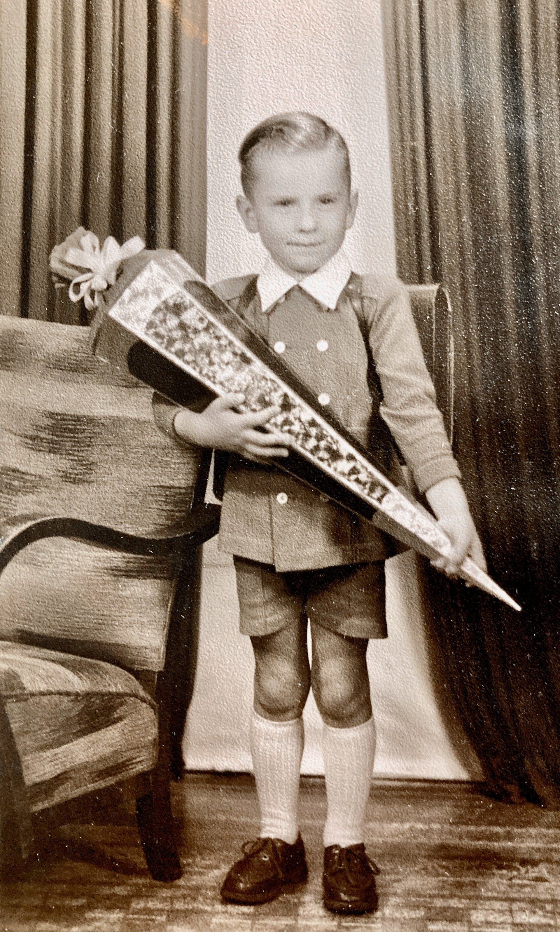 Auf einem Schwarzweißfoto hält ein kleiner Junge eine Schultüte.