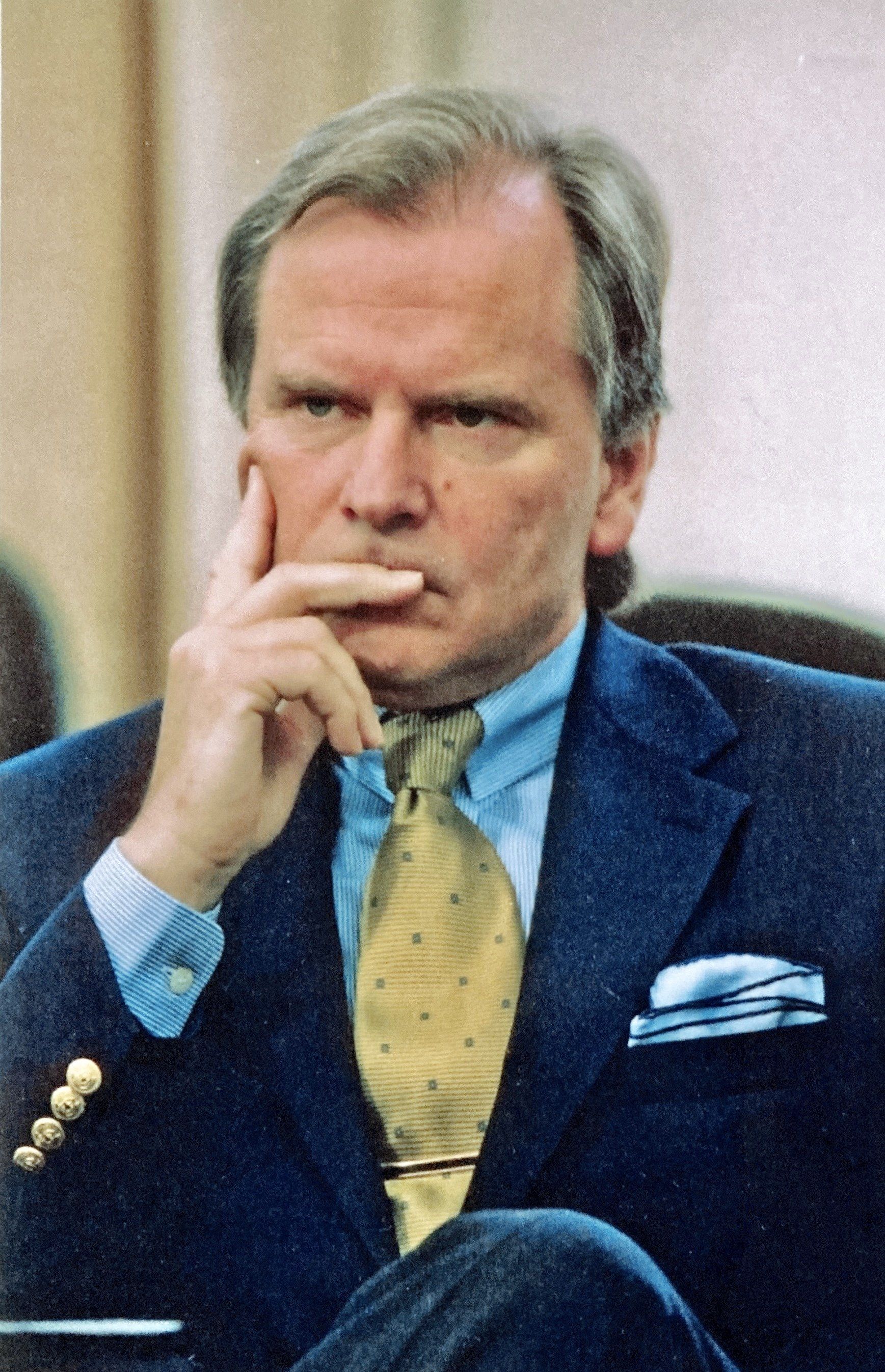 Ein Mann in Anzug und Krawatte sitzt mit der Hand am Kinn