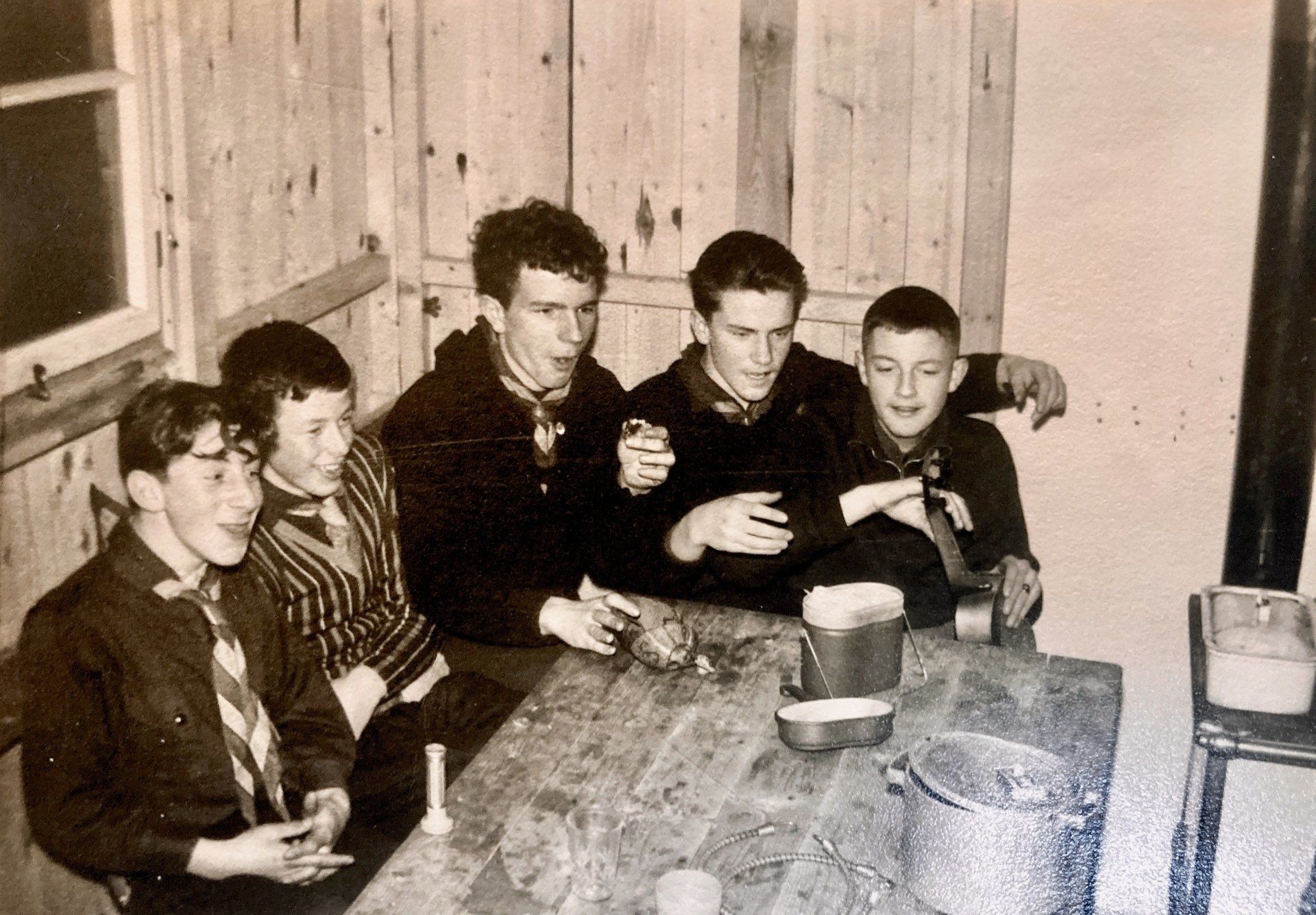 Auf einem Schwarzweißfoto sitzt eine Gruppe junger Männer um einen Tisch.