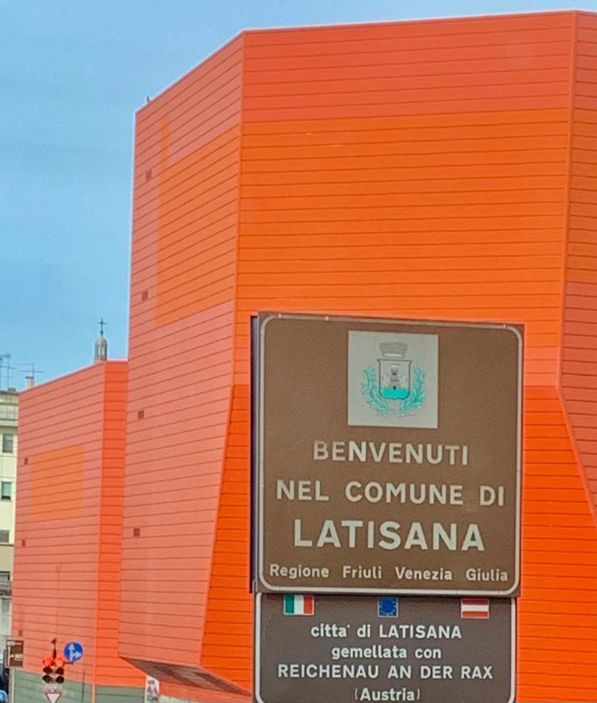 Willkommen in der Gemeinde Latisana. Schild vor einem orangefarbenen Gebäude