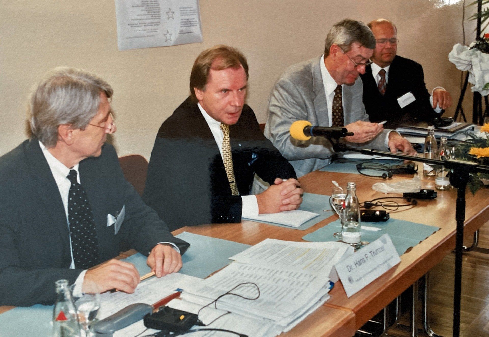 Eine Gruppe Männer sitzt an einem Tisch mit einem Namensschild mit der Aufschrift „Dr.“