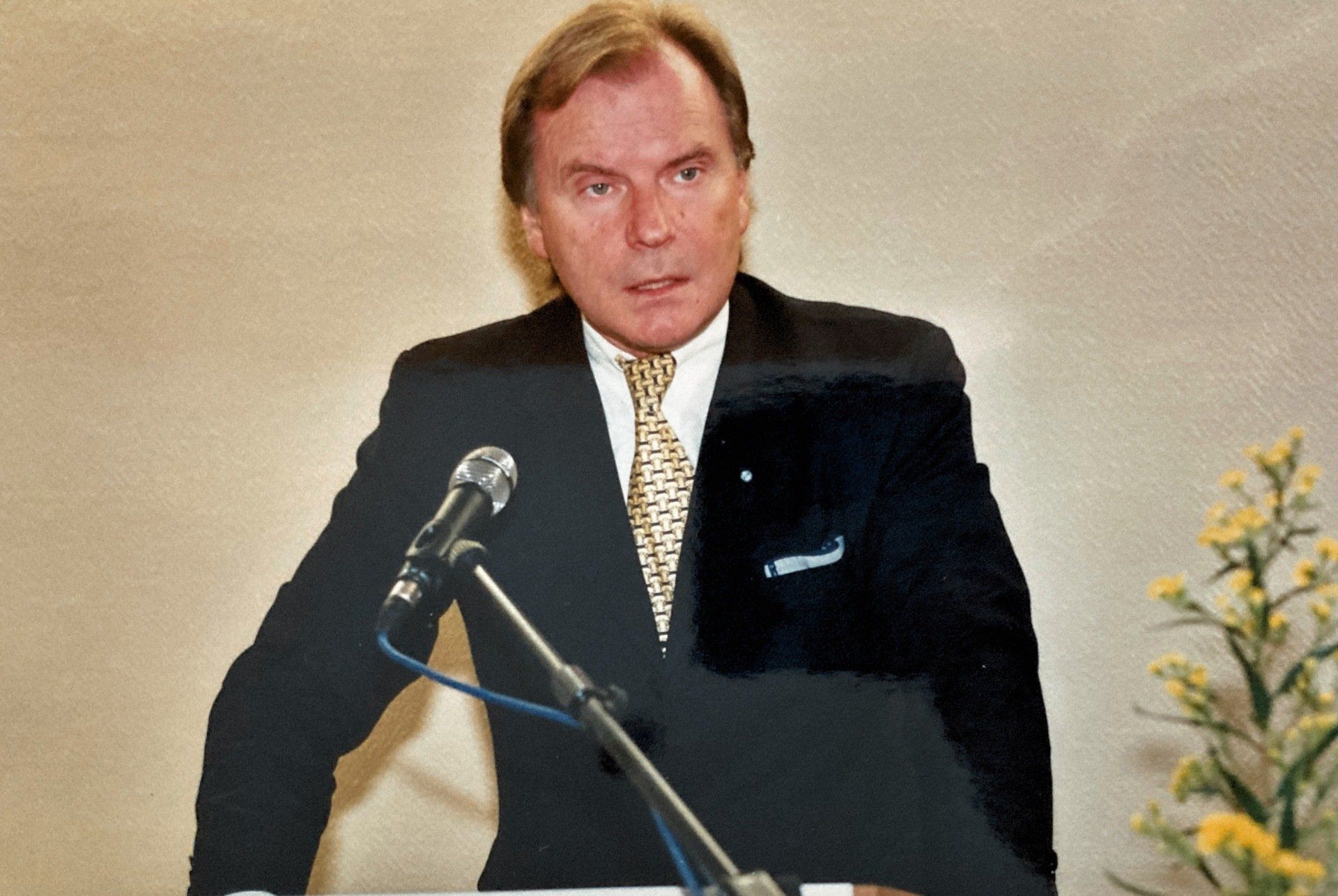 Ein Mann in Anzug und Krawatte spricht in ein Mikrofon