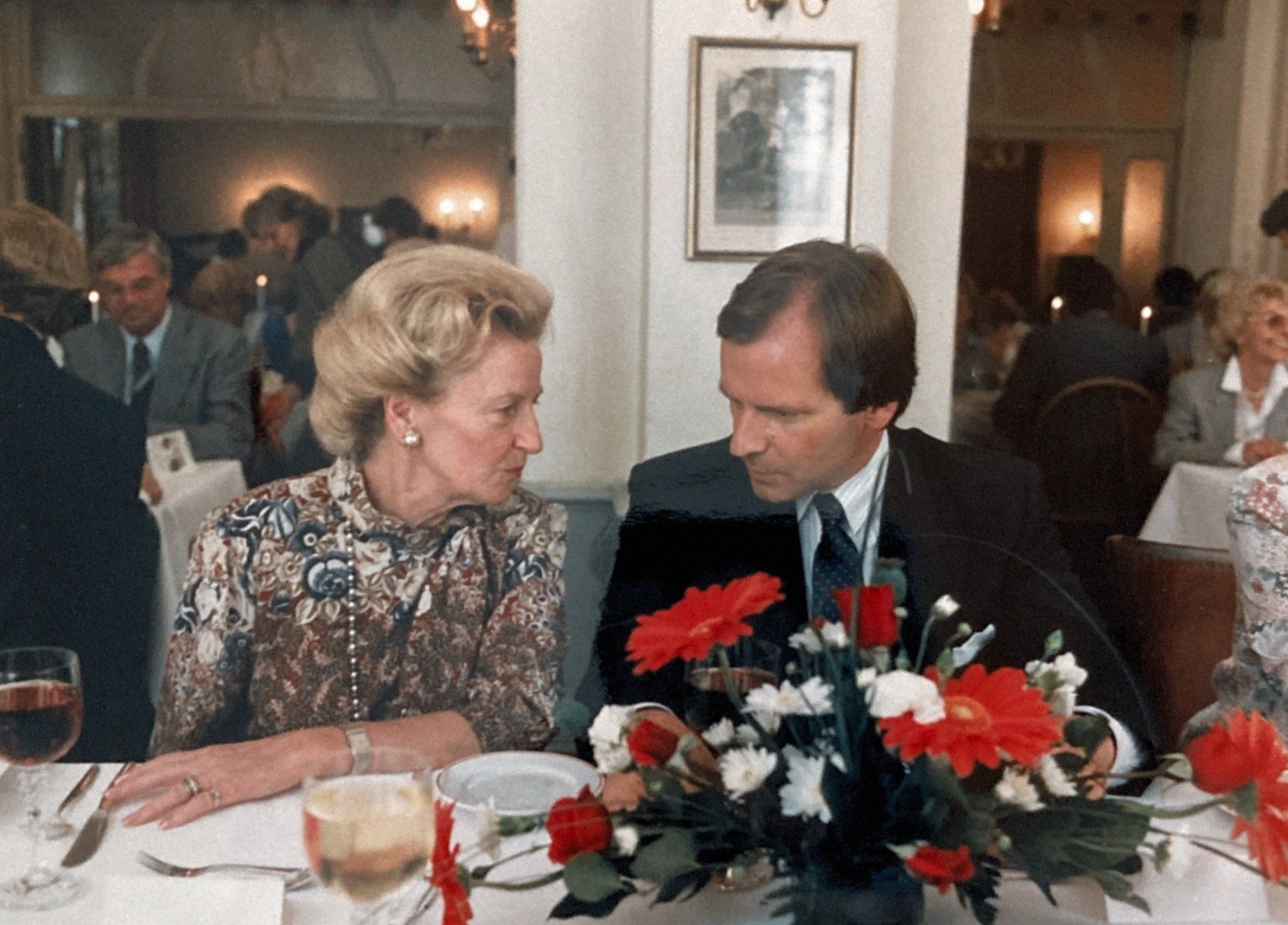 Ein Mann und eine Frau sitzen an einem Tisch mit Blumen vor ihnen