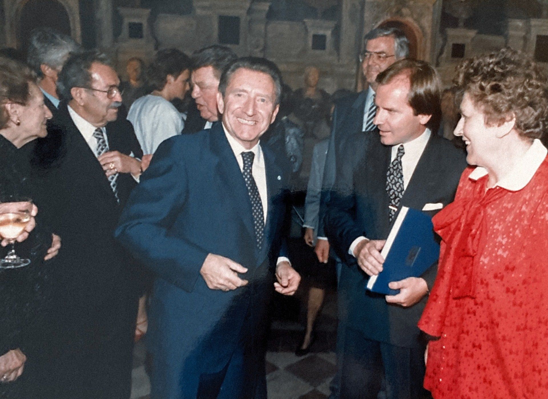 Eine Gruppe von Menschen steht um einen Mann im Anzug herum