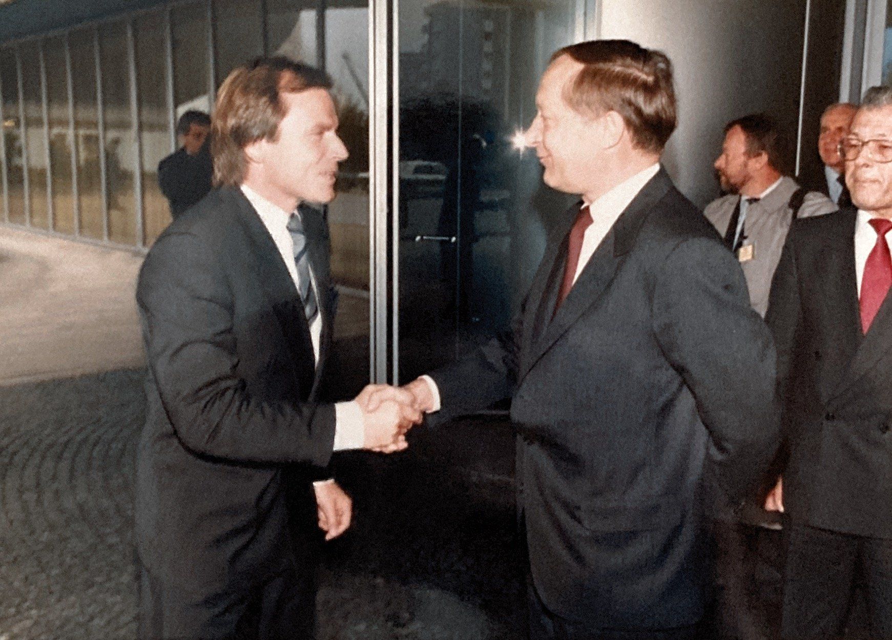 Ein Mann in Anzug und Krawatte schüttelt einem anderen Mann die Hand