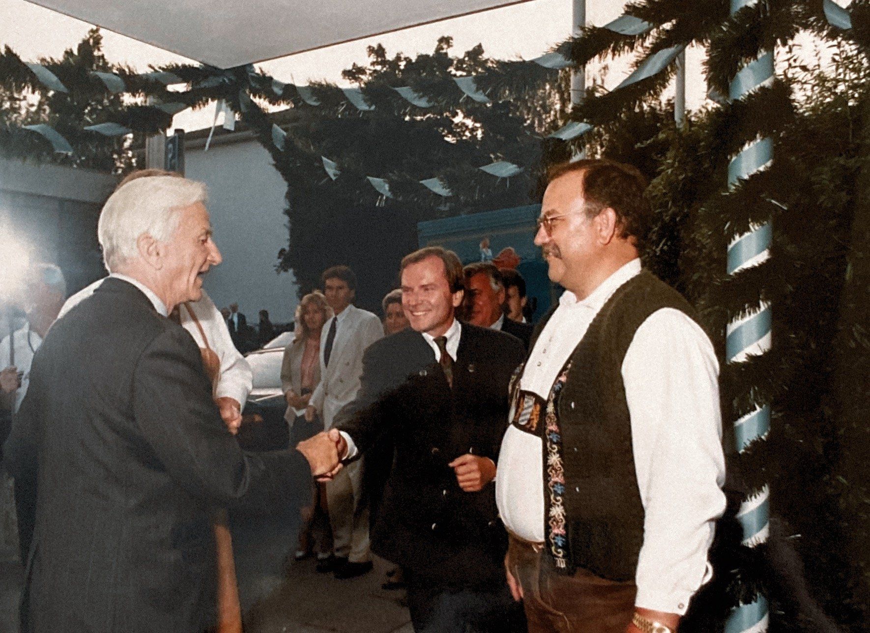 Ein Mann im Anzug schüttelt einem anderen Mann in einer Weste die Hand