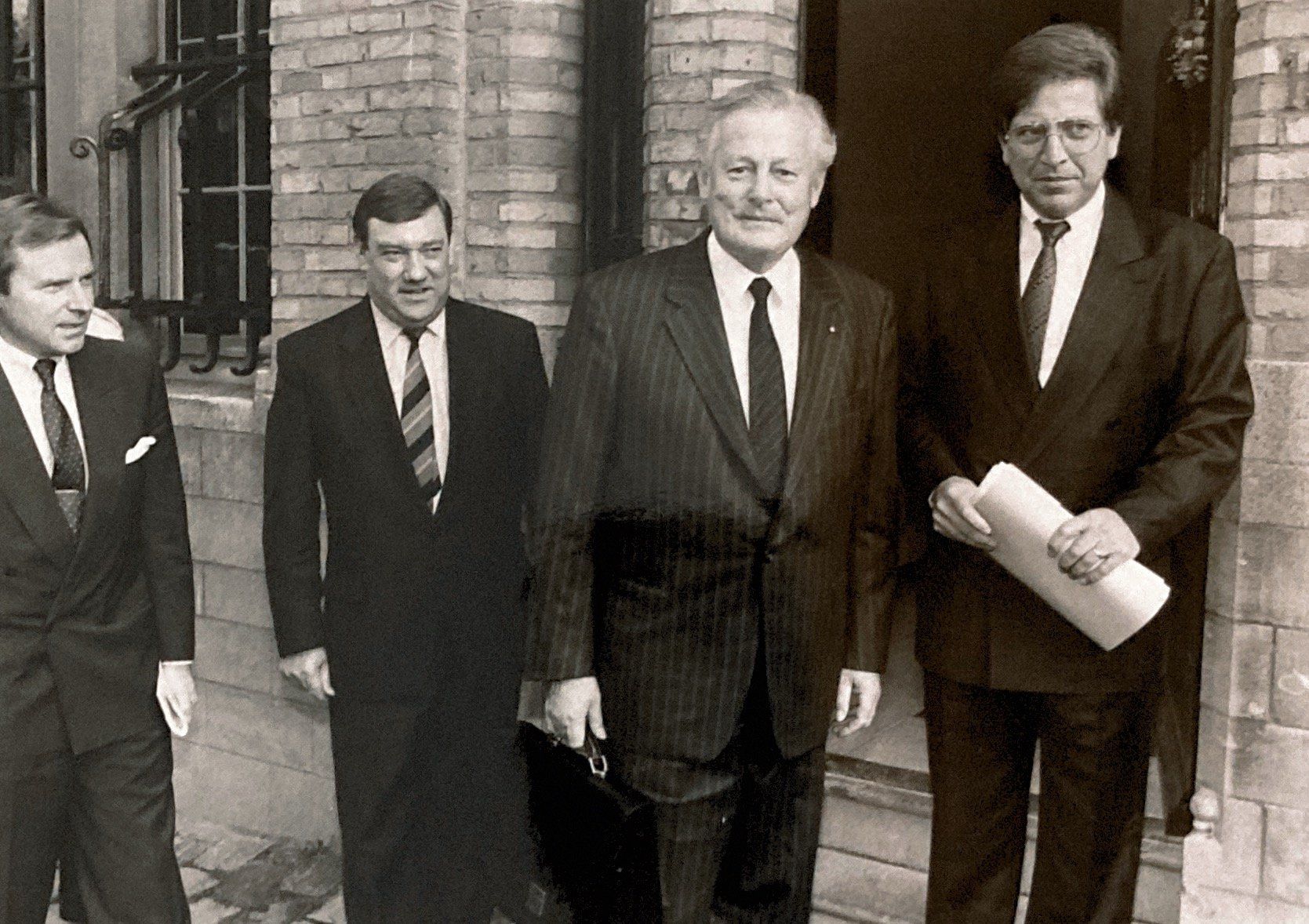 Ein Schwarzweißfoto von vier Männern in Anzug und Krawatte