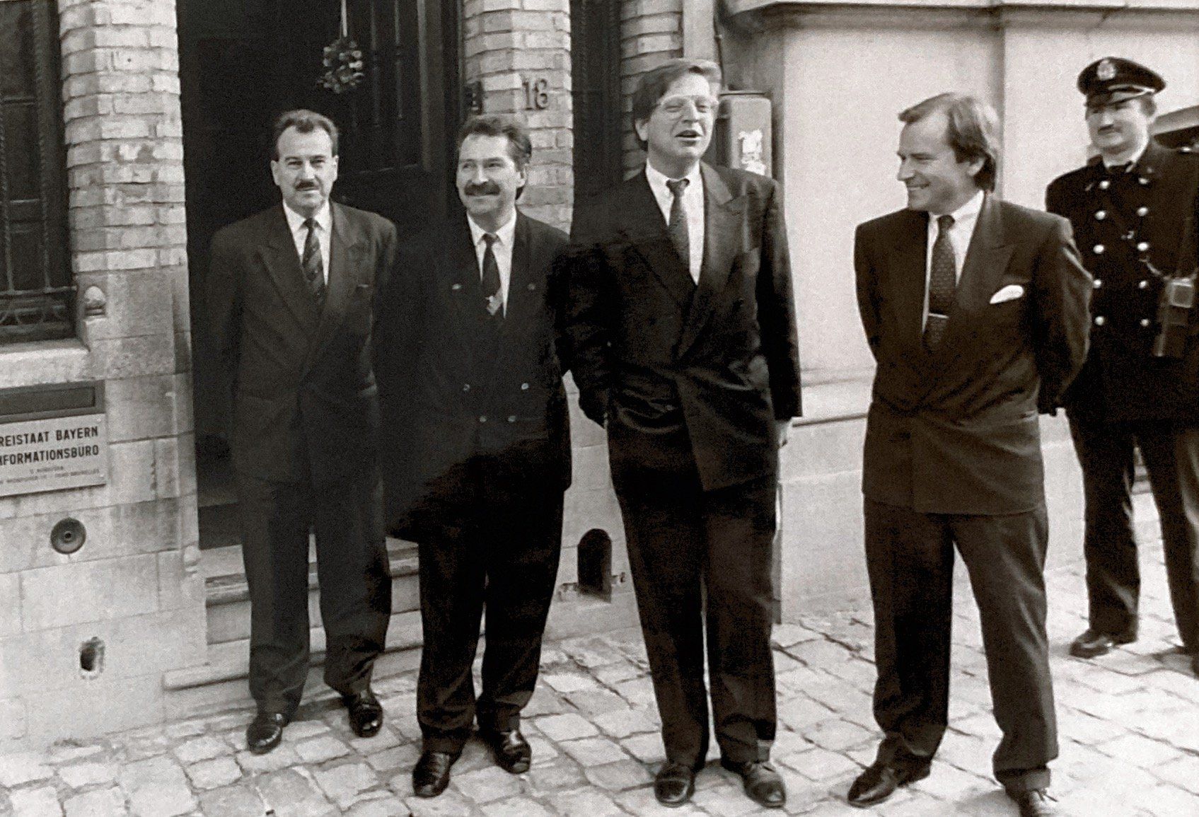 Eine Gruppe von Männern steht vor einem Gebäude mit der Nummer 16 darauf