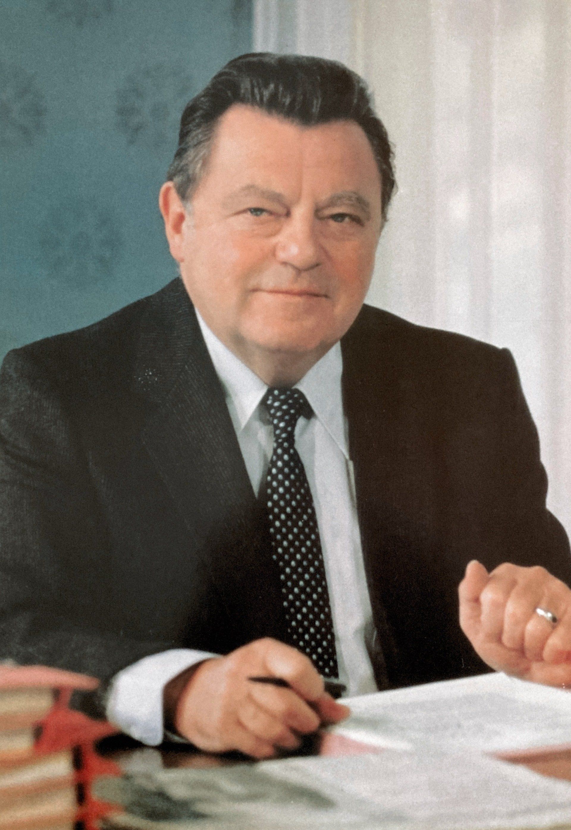 Ein Mann in Anzug und Krawatte sitzt an einem Schreibtisch