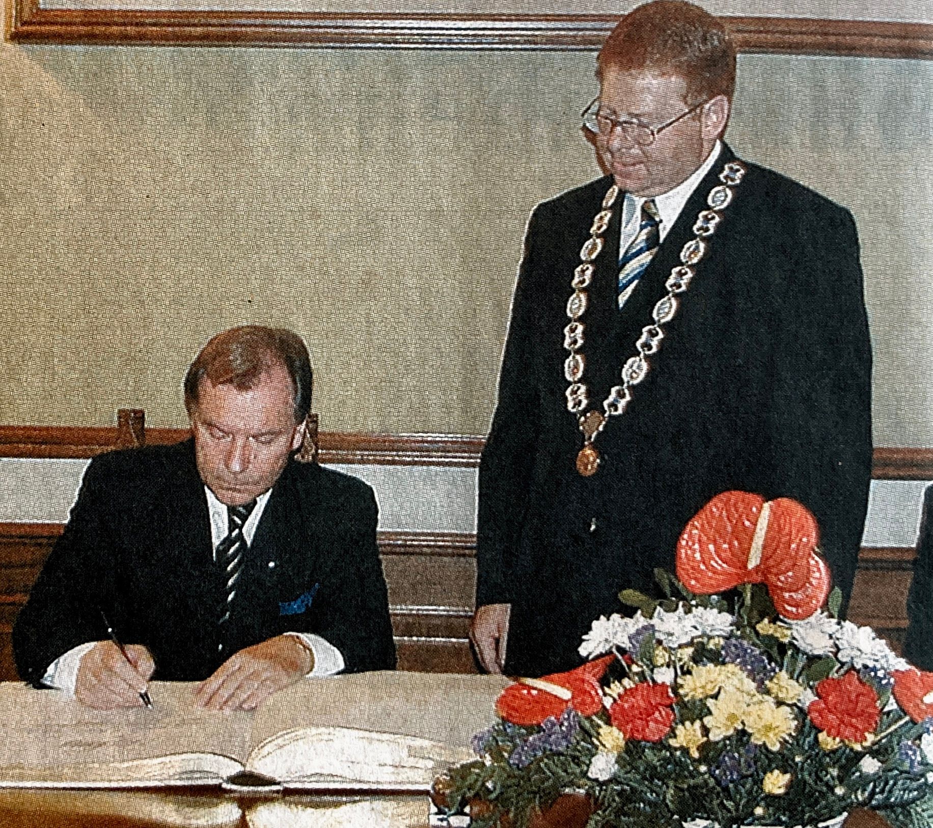 Ein Mann in Anzug und Krawatte unterschreibt ein Dokument