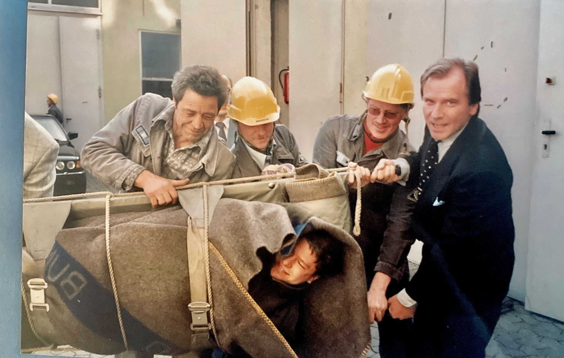Eine Gruppe von Männern mit Schutzhelmen trägt einen Mann in einer Decke