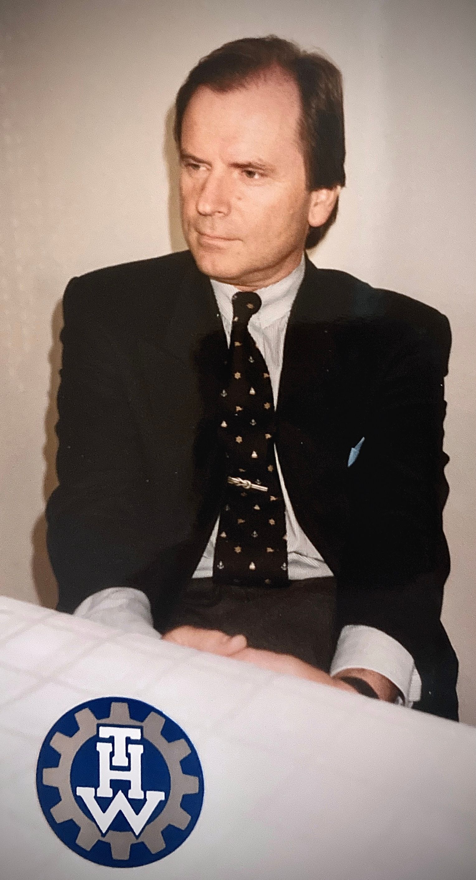 Ein Mann in Anzug und Krawatte sitzt an einem Tisch