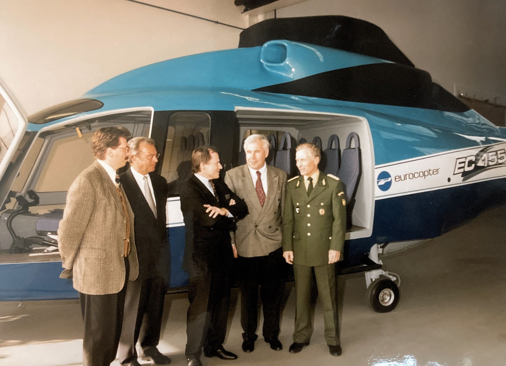 Eine Gruppe von Männern steht vor einem Hubschrauber mit der Aufschrift EC 456