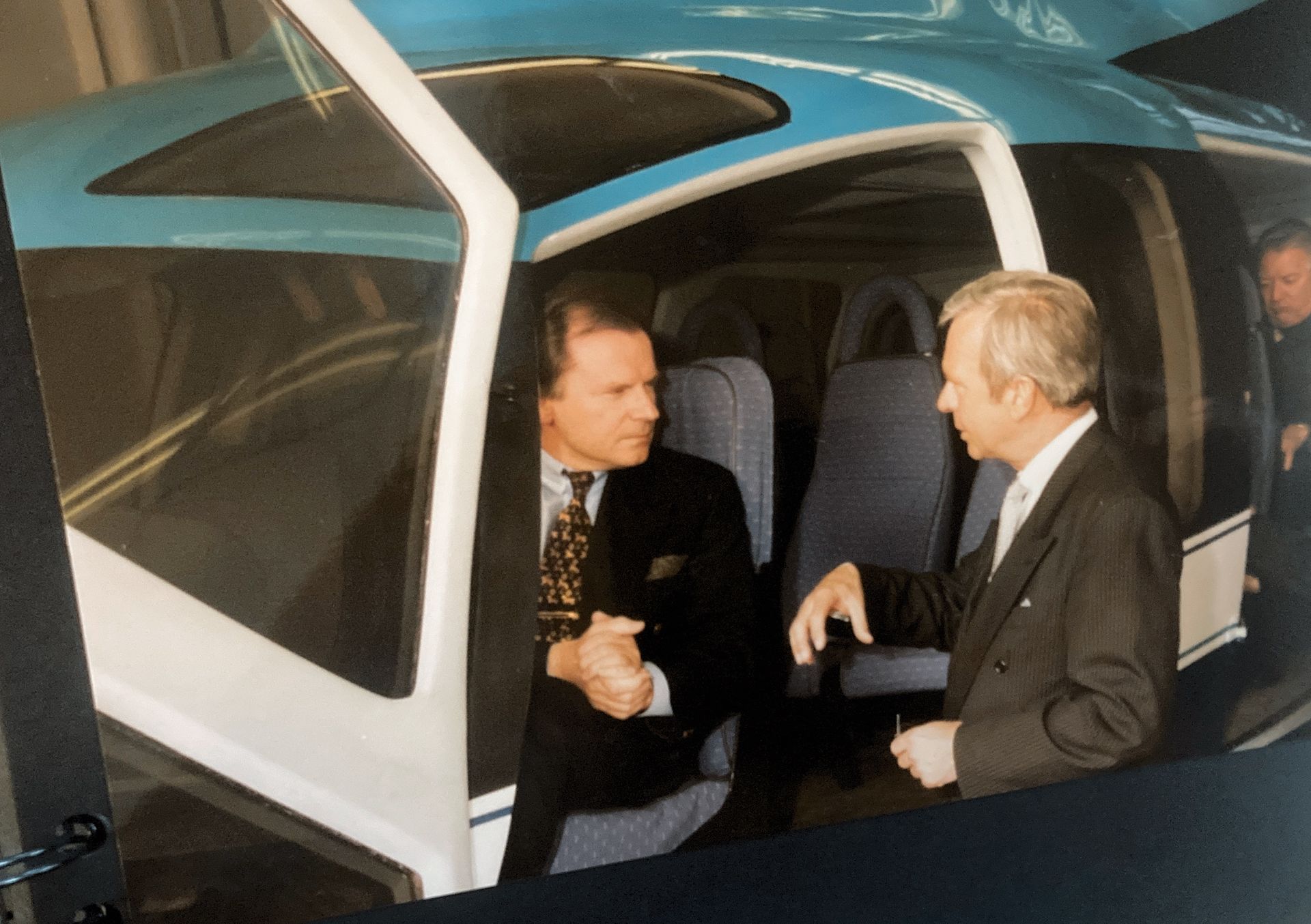 Ein Mann im Anzug spricht mit einem anderen Mann in einem Auto