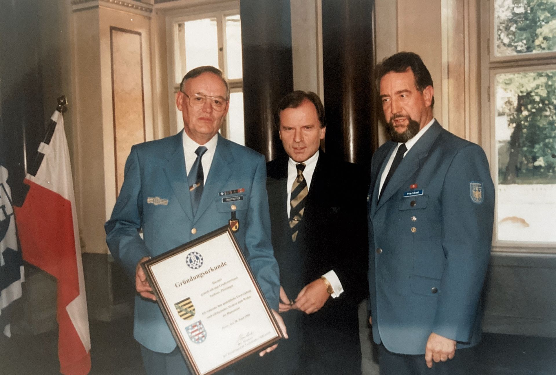 Ein Mann im blauen Anzug hält eine Urkunde in der Hand