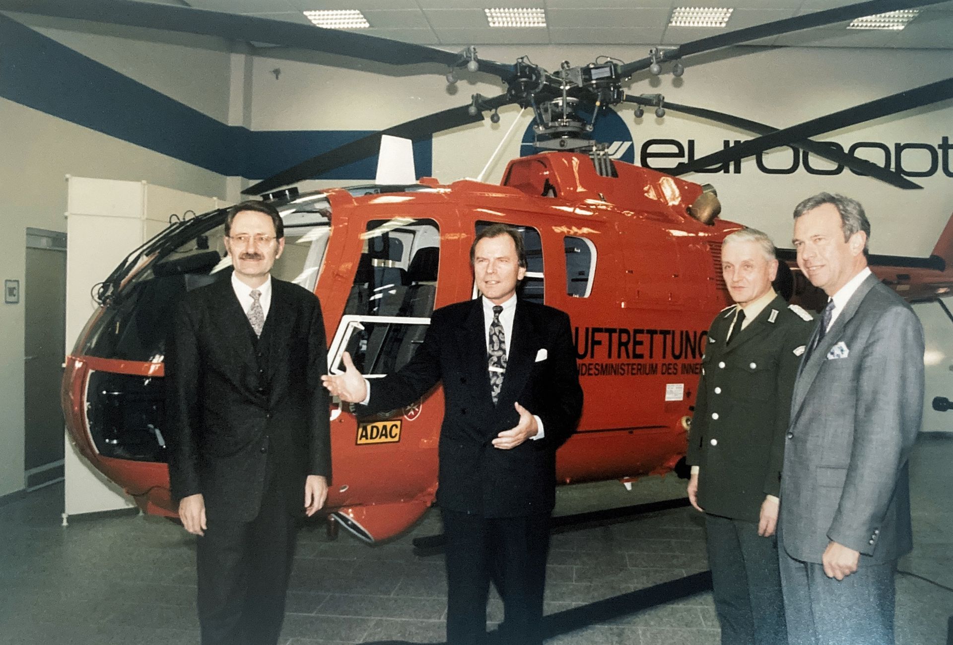 Eine Gruppe von Männern steht vor einem roten Hubschrauber mit der Aufschrift „Luftrettung“