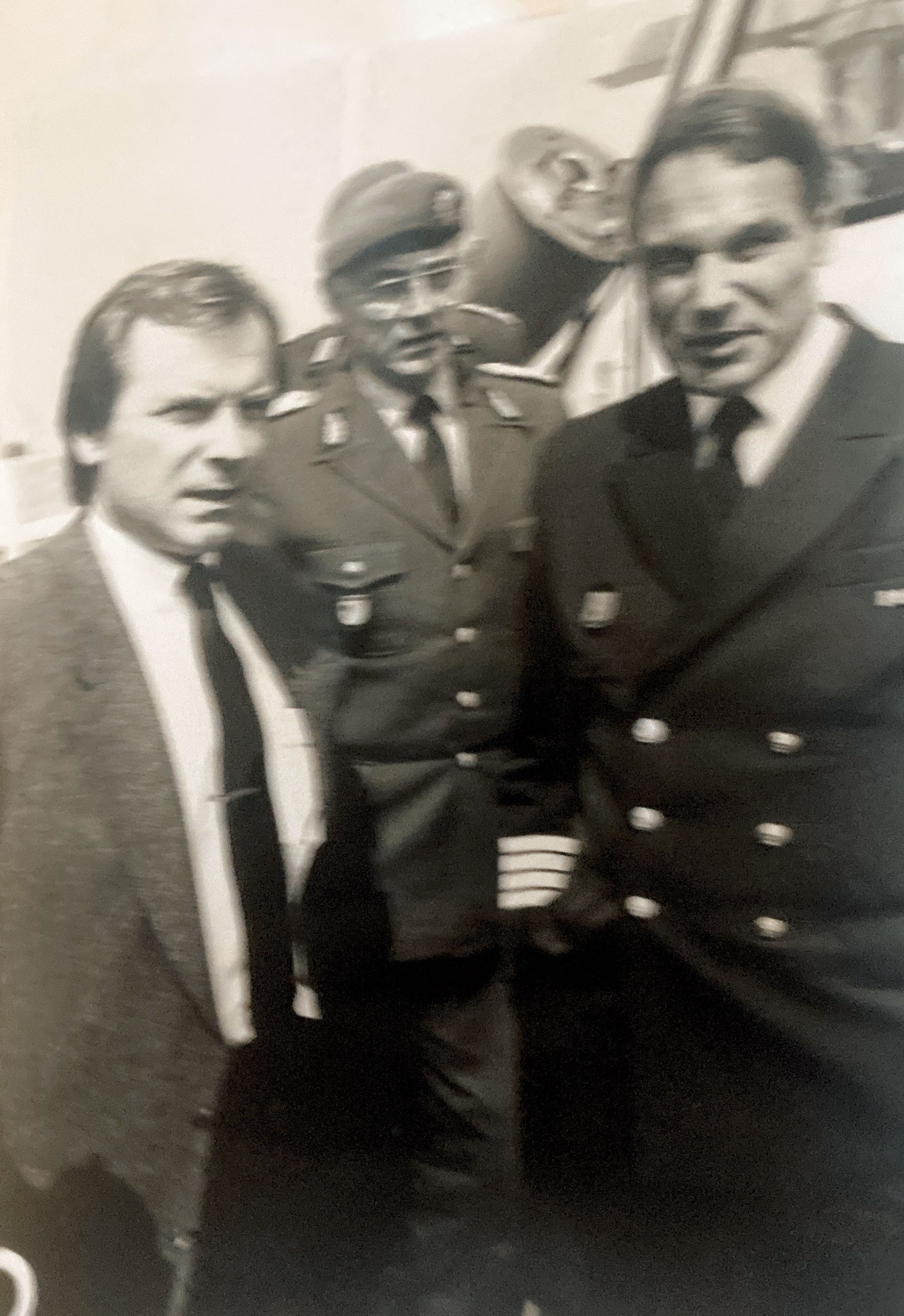 Auf einem Schwarzweißfoto stehen drei Männer in Anzug und Krawatte nebeneinander.