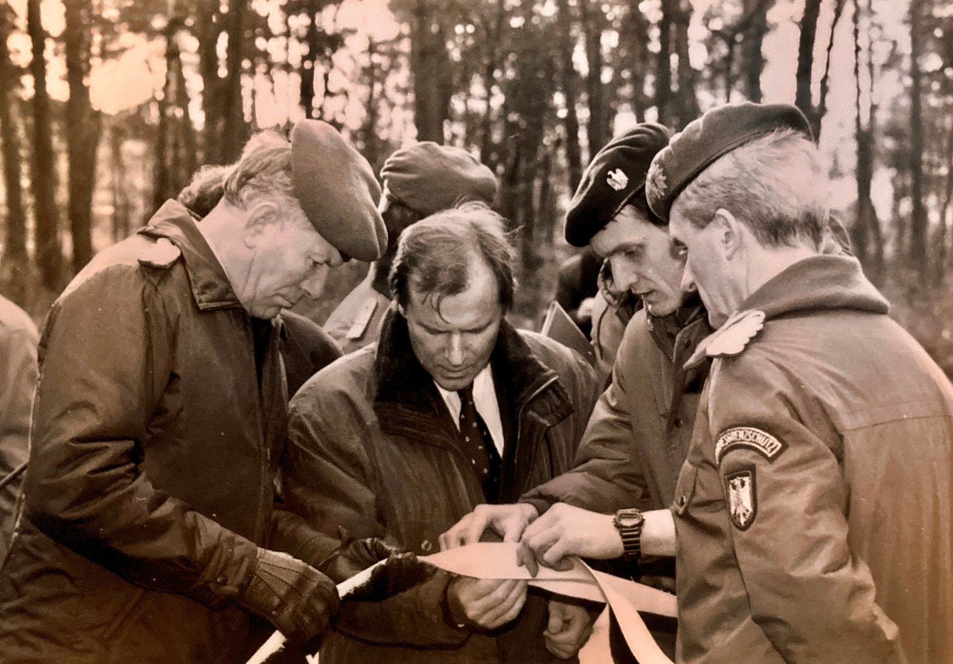 Eine Gruppe von Männern in Militäruniformen schaut sich ein Blatt Papier an.