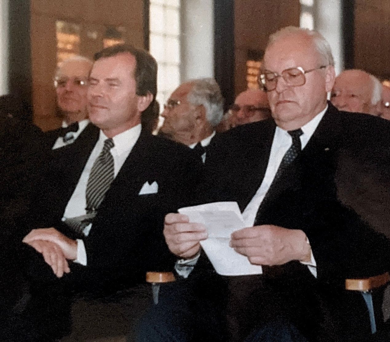 Eine Gruppe von Männern in Anzug und Krawatte sitzt in einem Raum