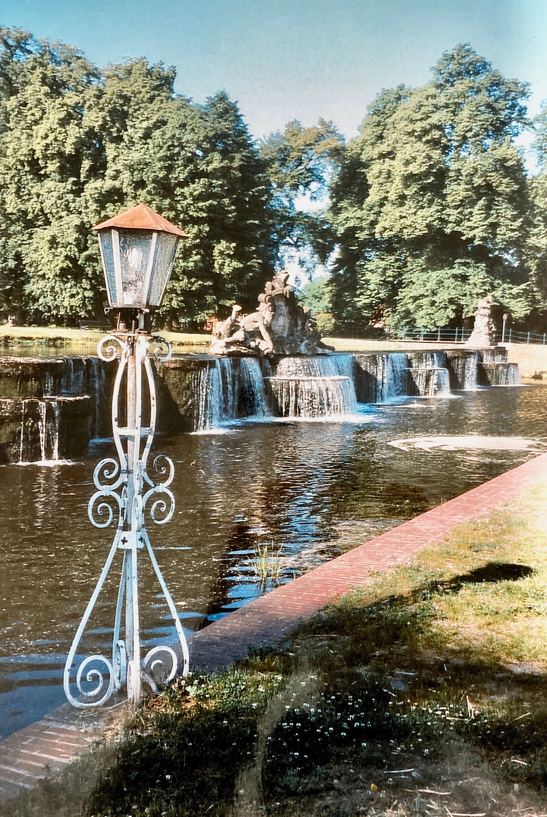 Ein Laternenpfahl vor einem Wasserfall in einem Park