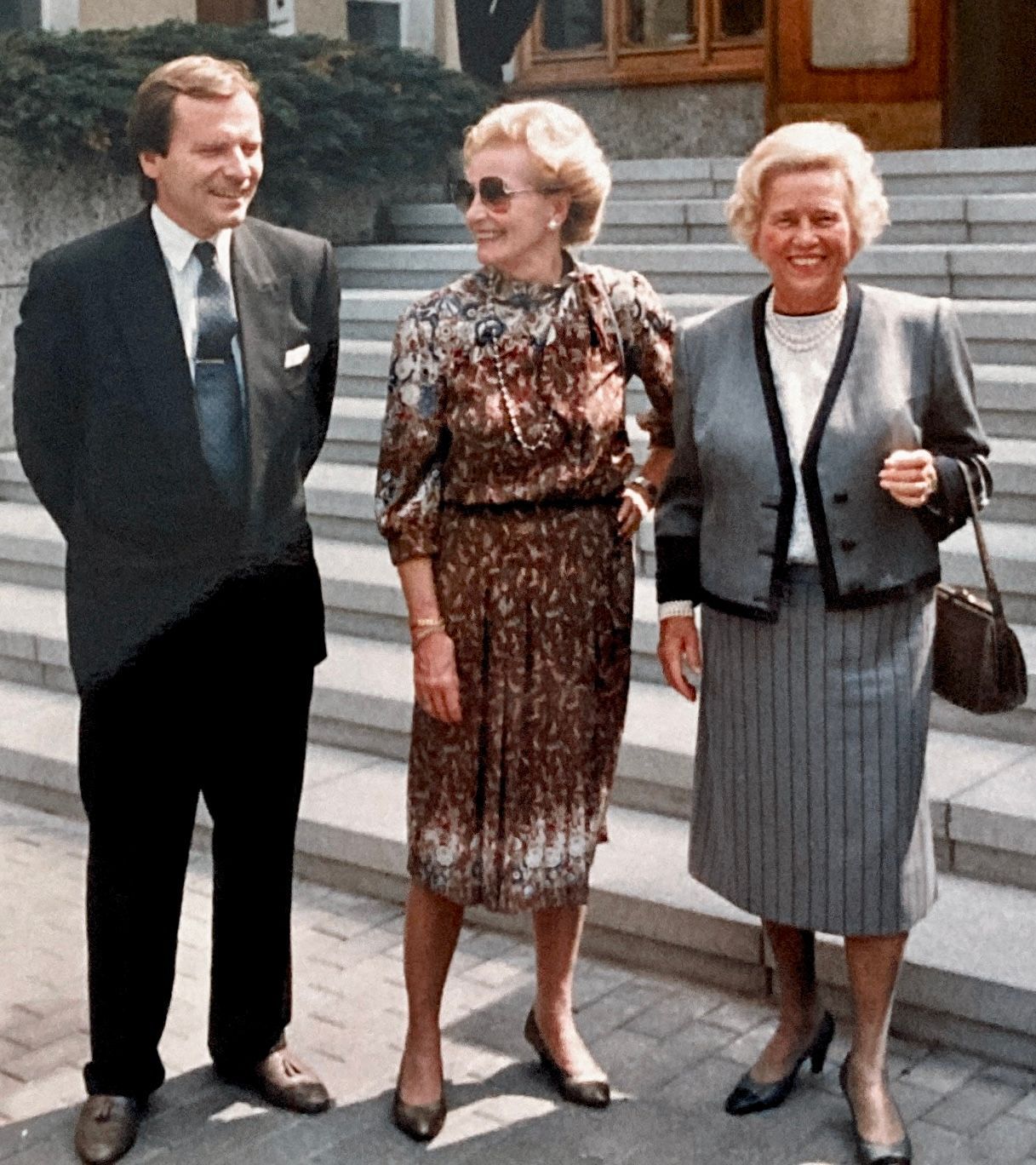 Ein Mann in Anzug und Krawatte steht neben zwei Frauen