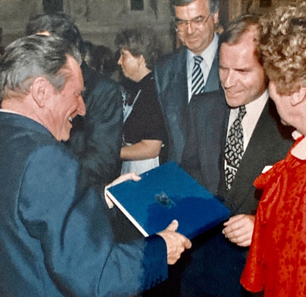 Ein Mann im Anzug hält ein blaues Buch