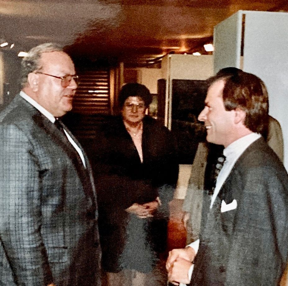 Ein Mann in Anzug und Krawatte spricht mit einem anderen Mann