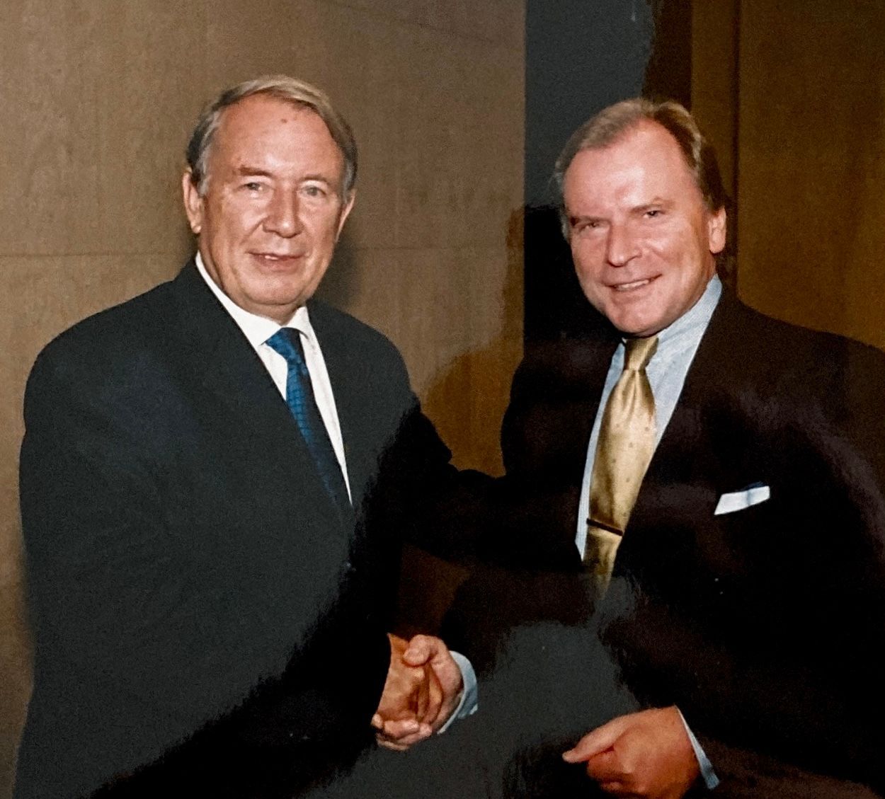 Zwei Männer in Anzug und Krawatte schütteln sich die Hände