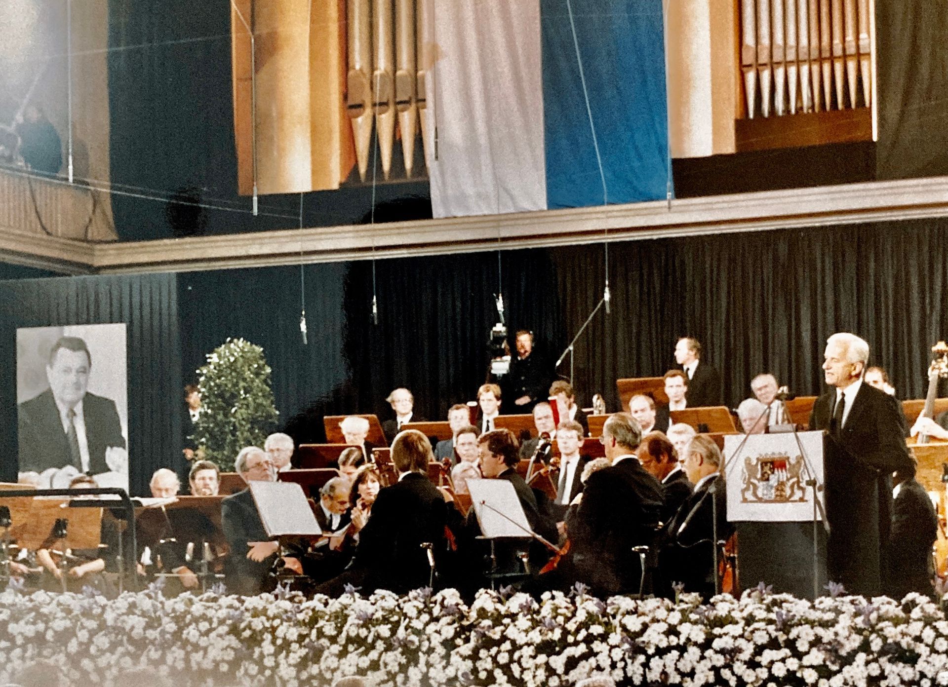 Ein Mann steht vor einem Orchester auf einer Bühne