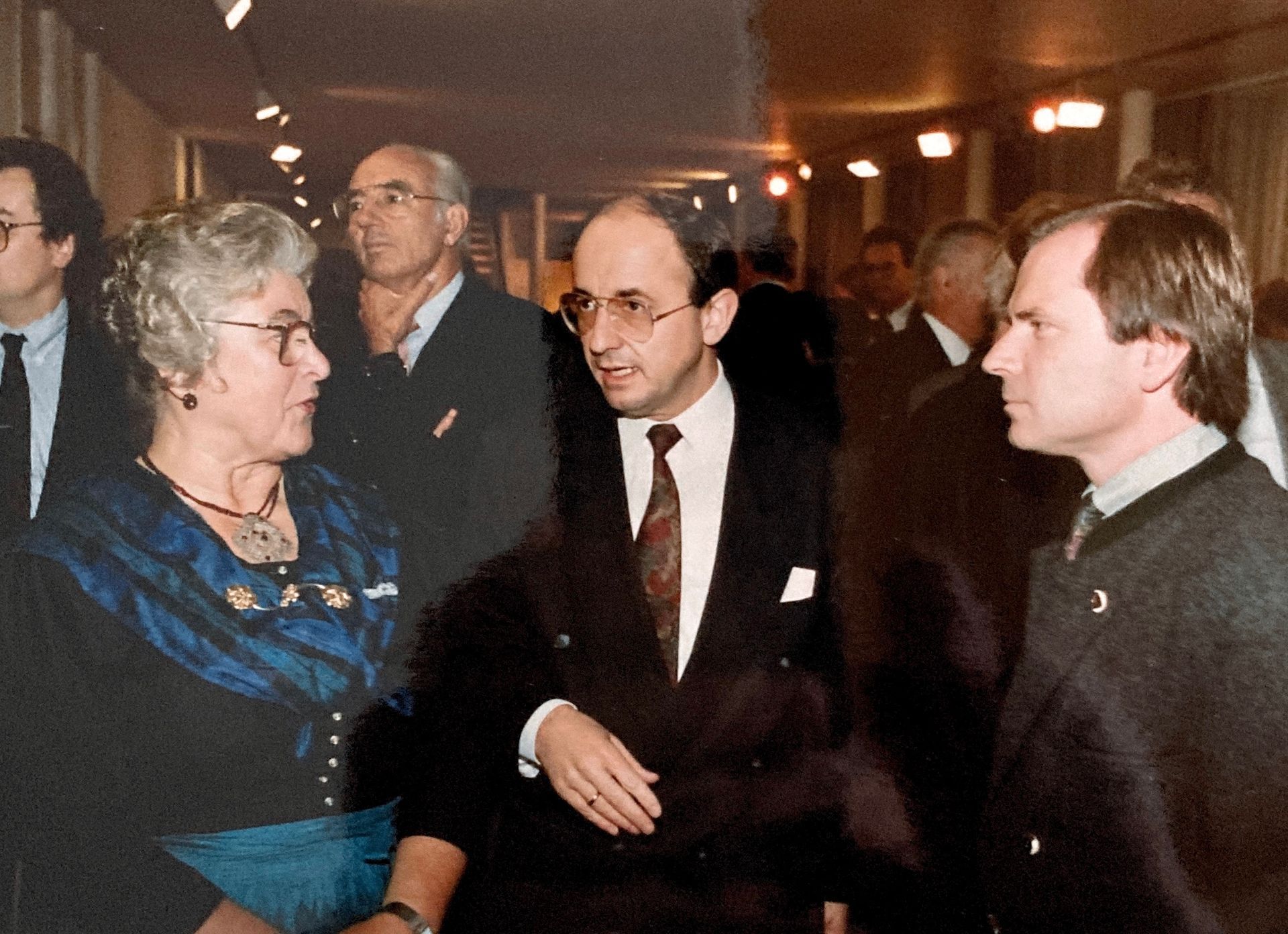 Ein Mann in Anzug und Krawatte spricht mit einer Frau in einem blauen Kleid