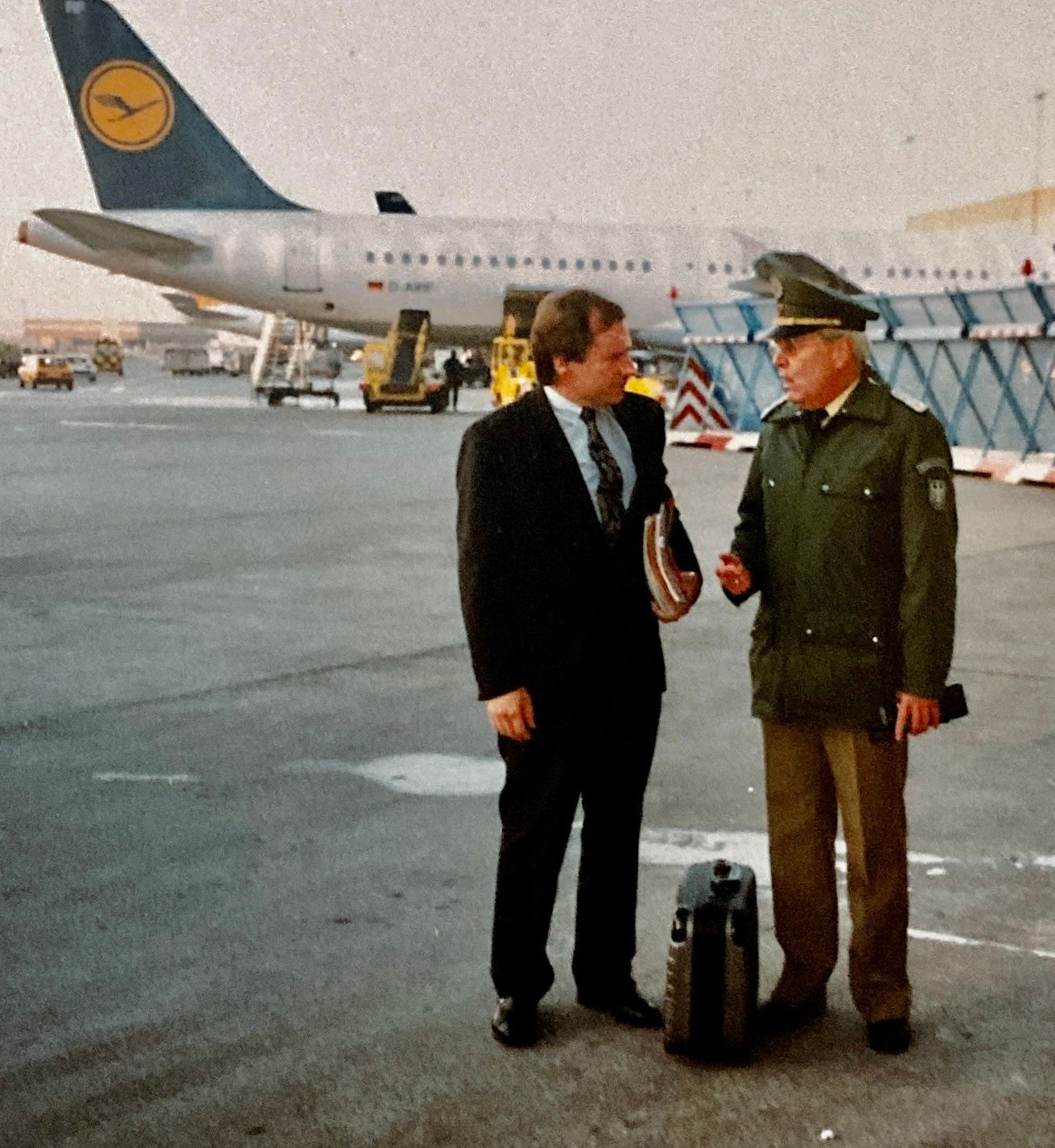 Zwei Männer stehen vor einem Flugzeug mit einer Uhr am Heck