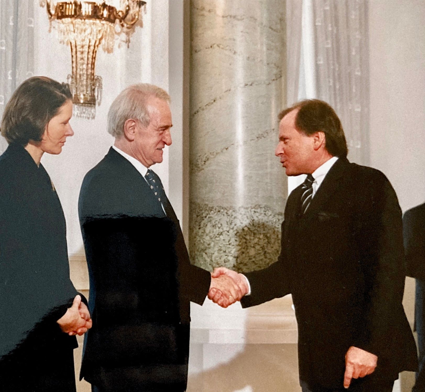 Ein Mann in Anzug und Krawatte schüttelt einem anderen Mann die Hand