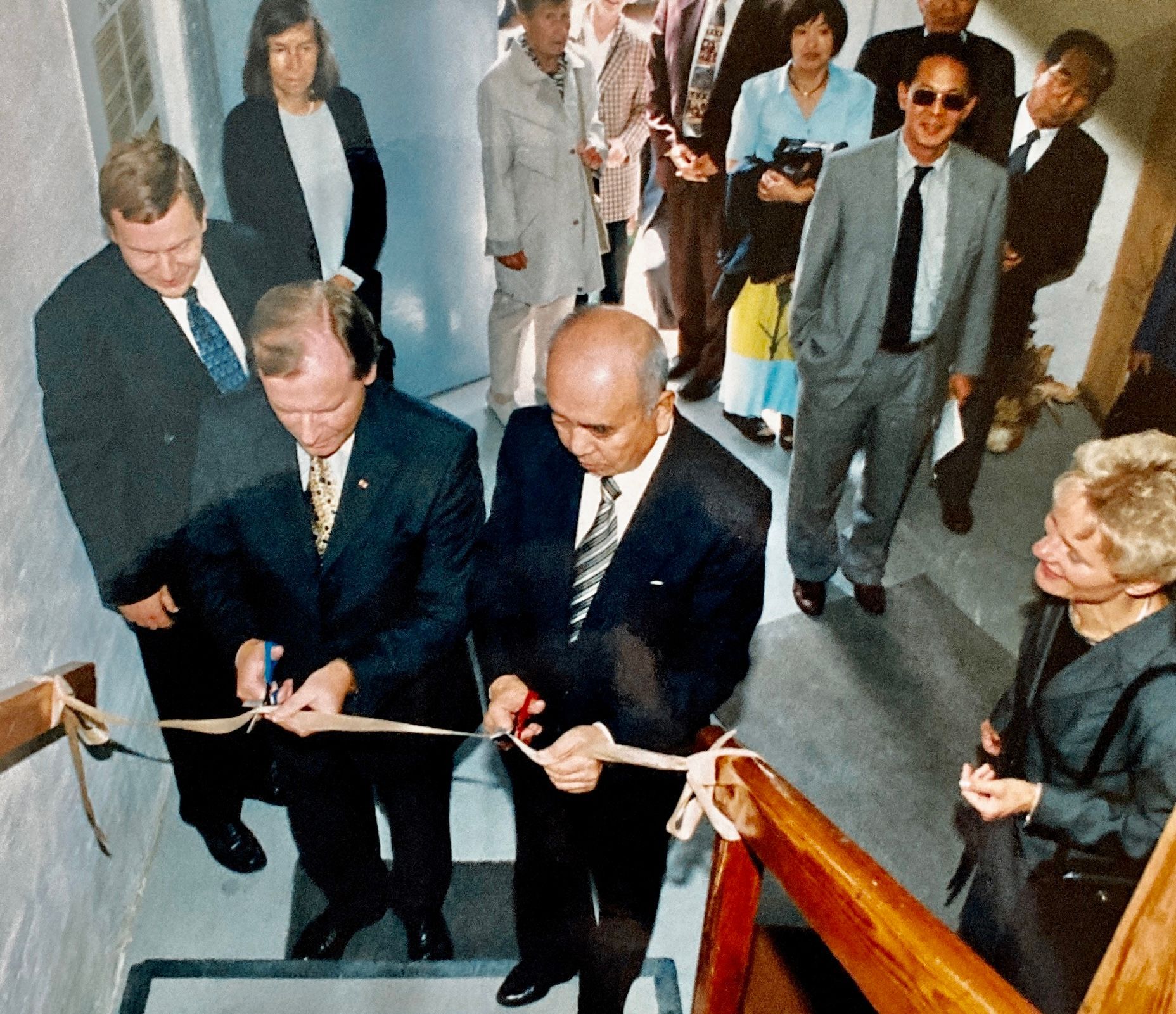 Eine Gruppe von Menschen in Anzug und Krawatte durchschneidet ein Band