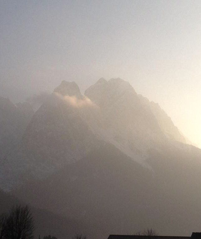Die Sonne scheint durch die Wolken auf den Bergen.