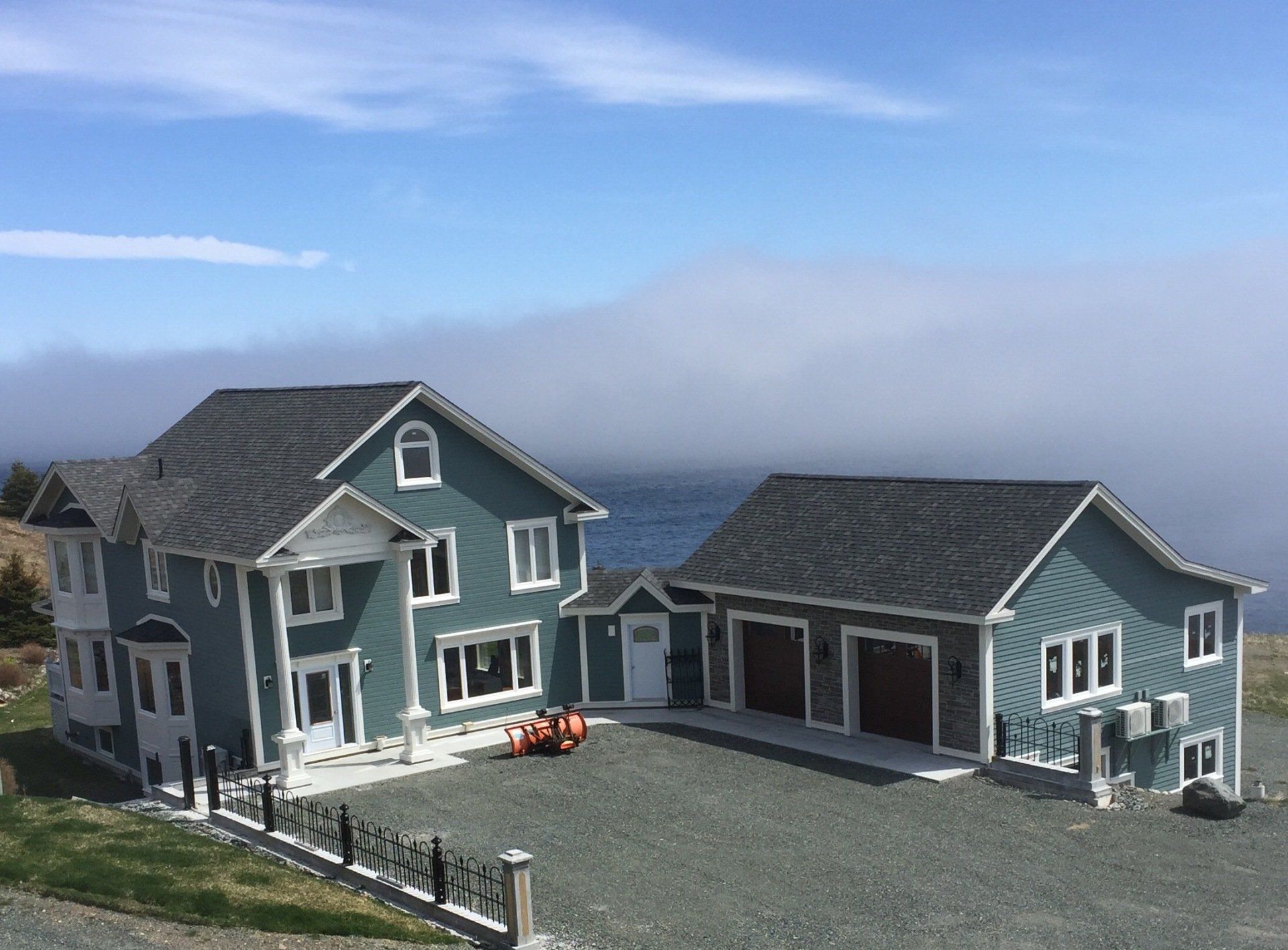 Ein paar Häuser, die nebeneinander auf einem Hügel mit Blick auf den Ozean stehen.