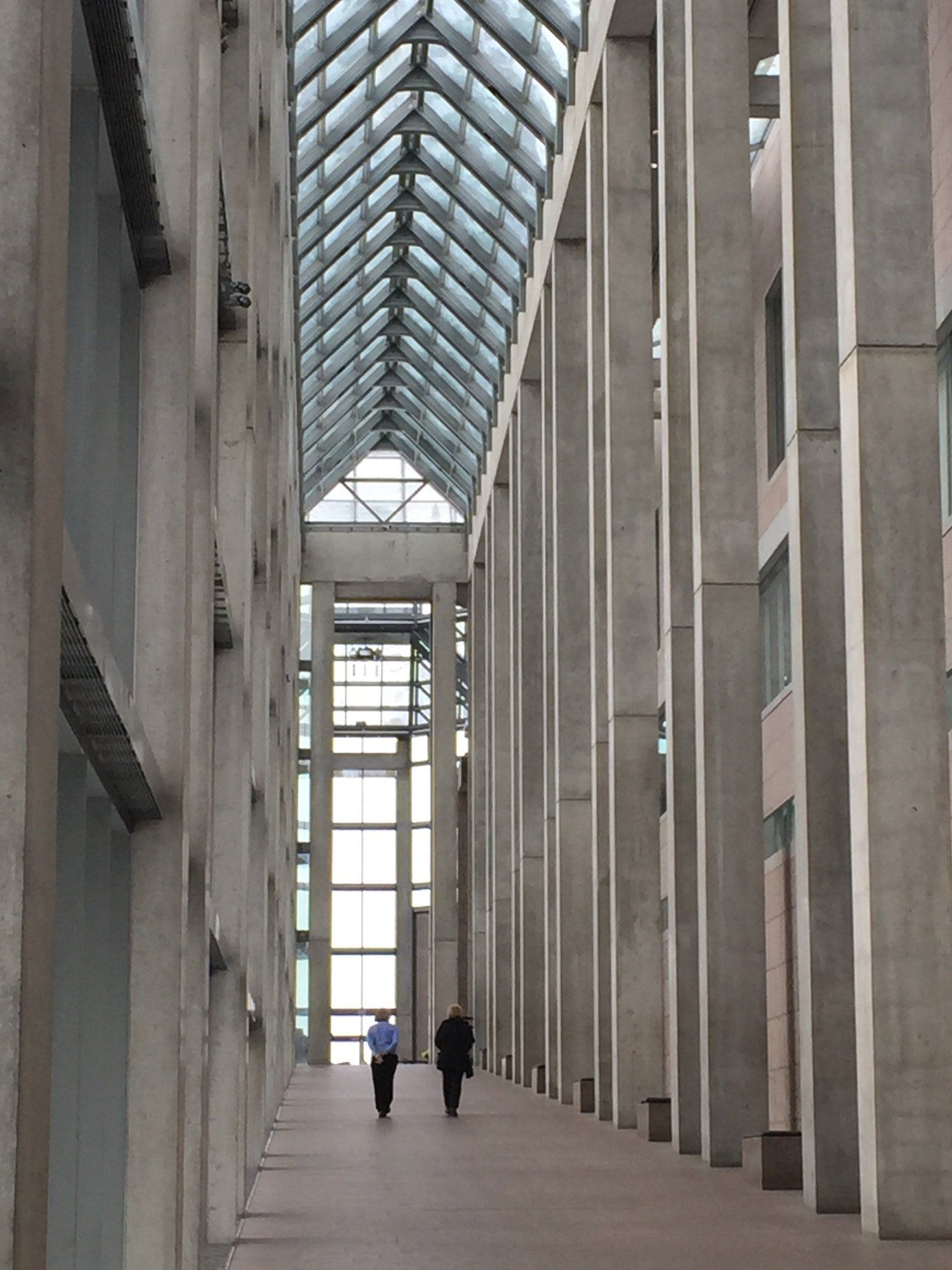 Zwei Menschen gehen einen langen Flur in einem Gebäude entlang