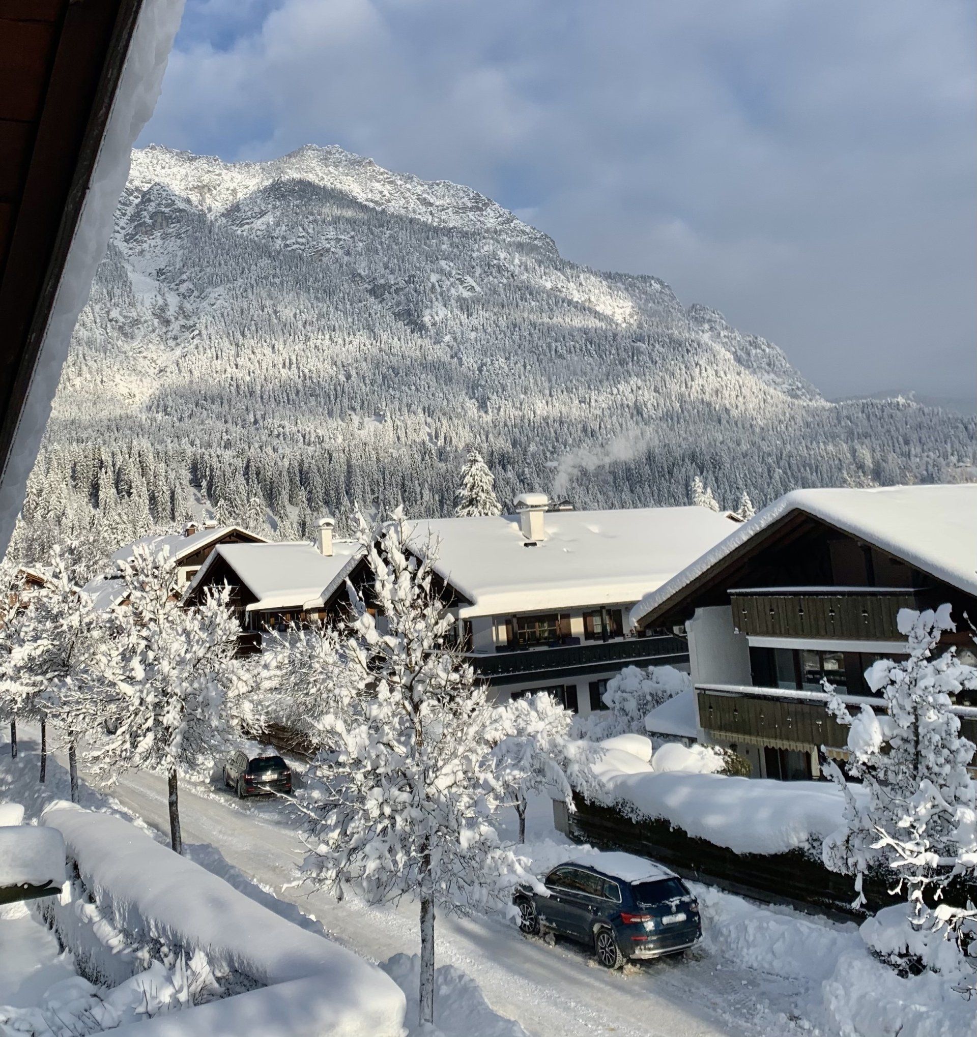 Ein Auto fährt eine verschneite Straße mit Bergen im Hintergrund hinunter