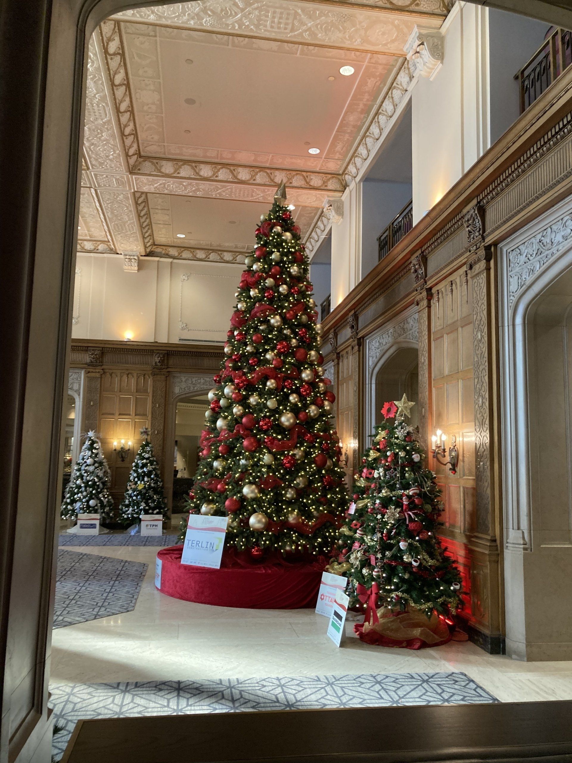 In der Lobby eines Gebäudes stehen viele Weihnachtsbäume.
